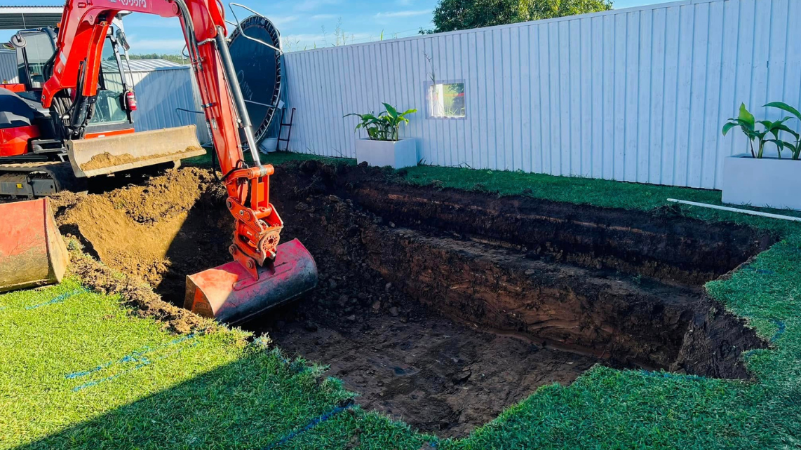 An excavator digging to prepare for fibreglass installation, taken and done by Pool Professionals Mackay