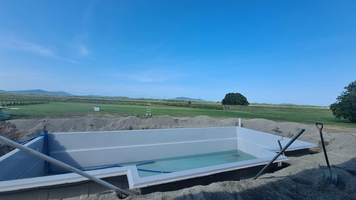 An image of a fibreglass pool already sitting on pool bedding, being filled by water at the same rate of backfilling, taken and installed by Pool Professionals Mackay