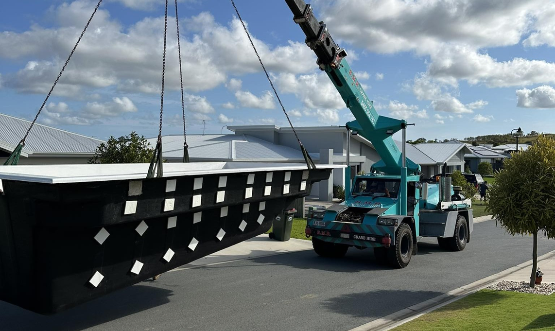A mobile crane lifting a fibreglass pool shell to deliver on site for installation, taken and done by Pool Professionals Mackay