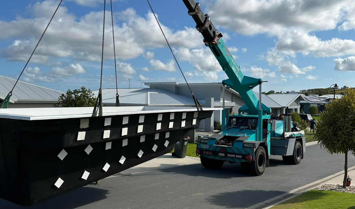 An image of a mobile crane lifting a fibreglass pool shell to deliver on site for installation, taken and done by Pool Professionals Mackay