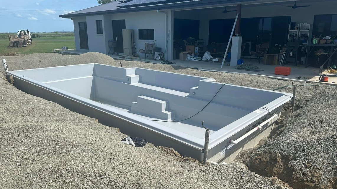 A fibreglass pool already placed above the bedding with unfinished backfill, installed and taken by Pool Professionals Mackay