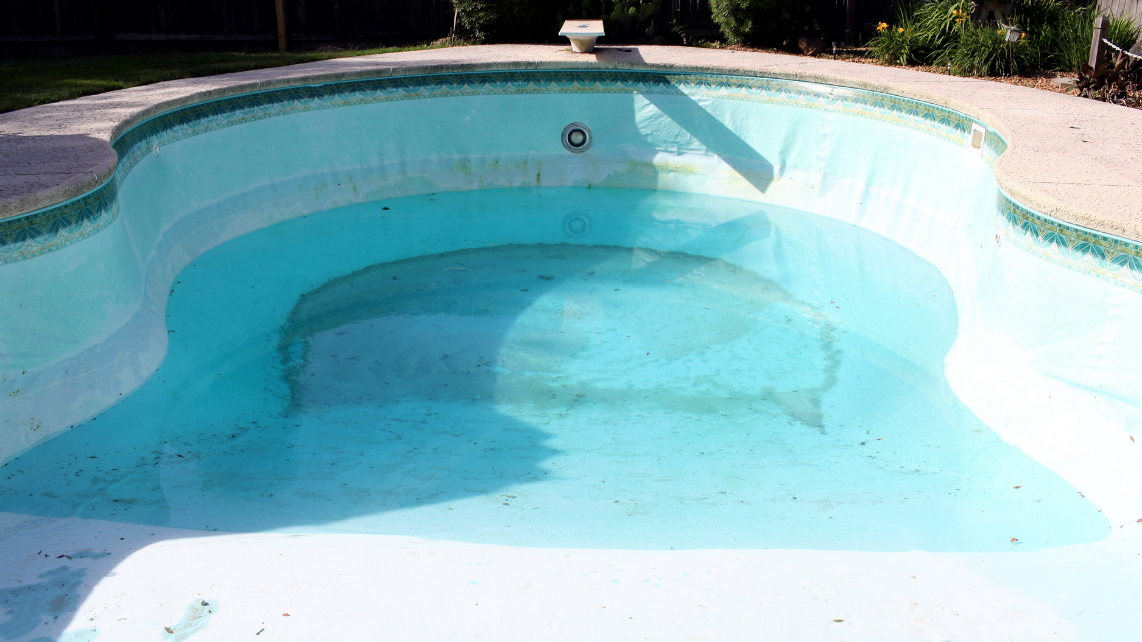 A pool with worn pool liner and half-full of water