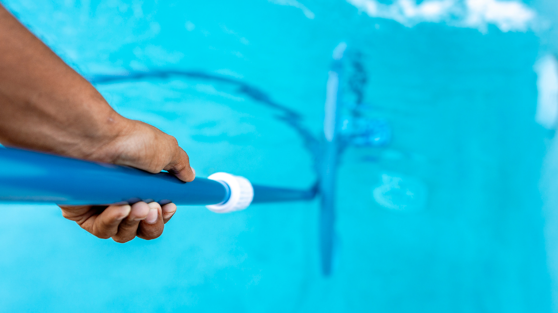 A person cleaning their pool using a fibreglass pool-safe vacuum cleaner