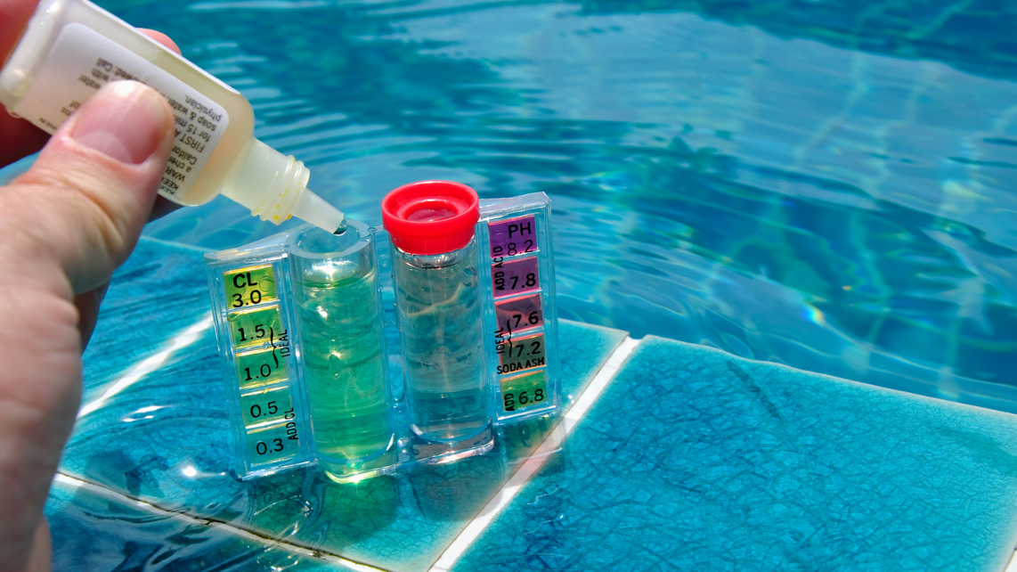 An image of a hand doing a pool water test using a liquid test kit