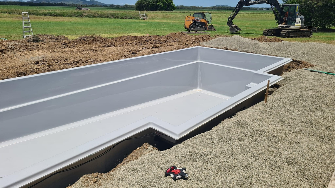 A fibreglass pool shell already placed on the excavated soil with proper bedding beneath, installed and taken by the Pool Professionals Mackay