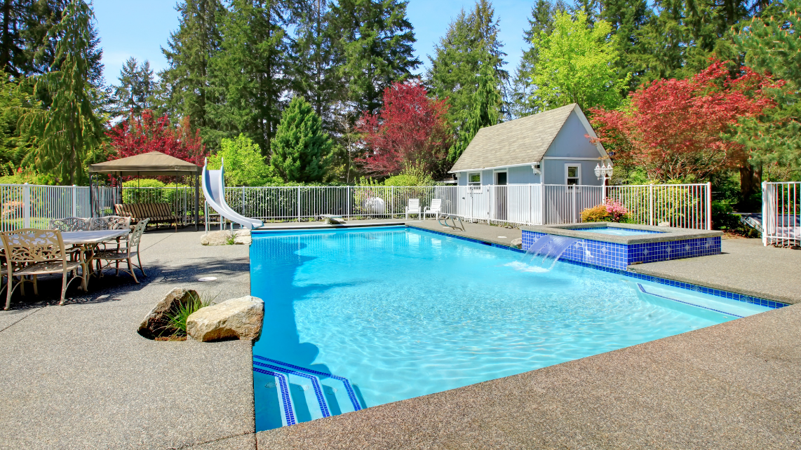 An image of a concrete pool from a backyard of someone, with many trees surrounding it